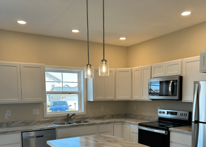 Modern kitchen with recessed lighting in the ceiling and two pendant lights over the island, showcasing clean design and efficient lighting layout.