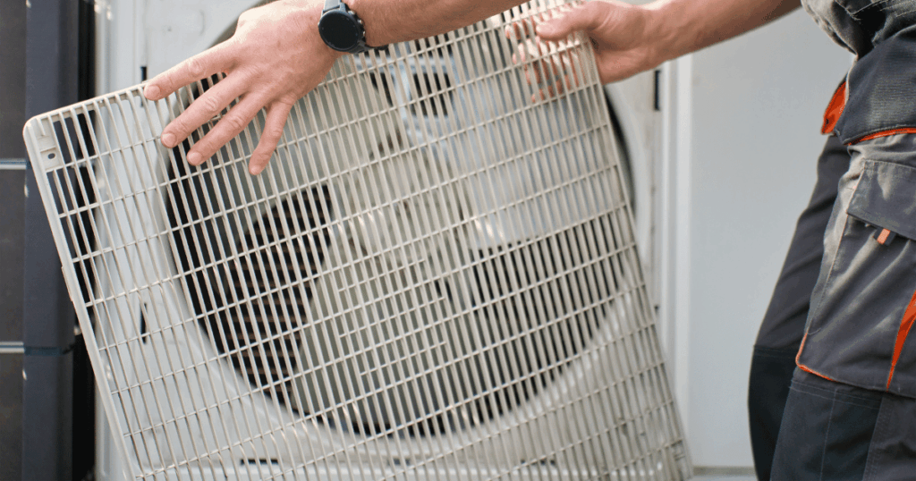 HVAC technician removing the front panel of an outdoor heat pump unit during installation